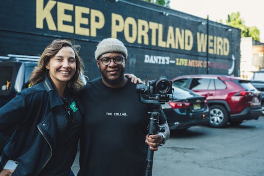 Two photographers smiling in front of the iconic Keep Portland Weird mural.